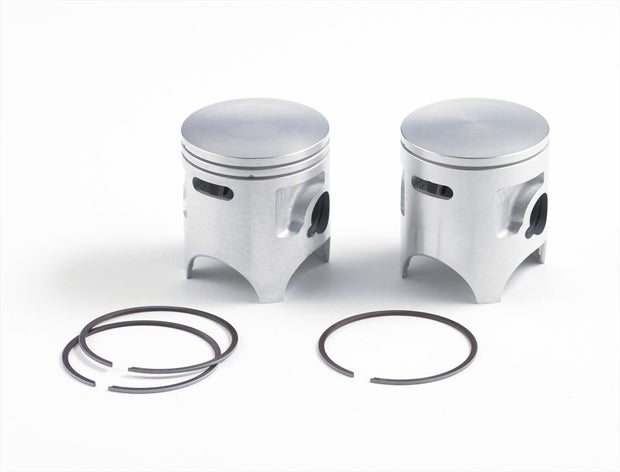 The previous two-ring piston (left) is replaced with a single-ring piston to reduce friction on the KX85 and KX100 for 2014. 
