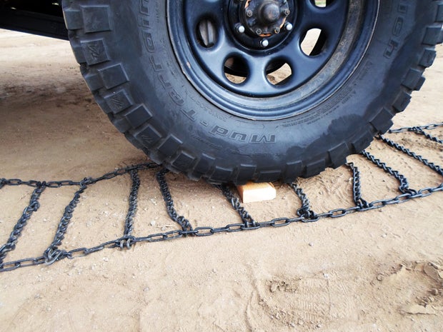 The board keeps the tire off the chains and provide room to adjust them. 