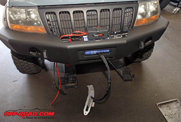 With the winch seated on the bumper, the hawse fairlead is placed through the front opening before it is bolted in place, and the winch wiring is run behind the bumper to it can be fed through the engine compartment to connect to the battery. 