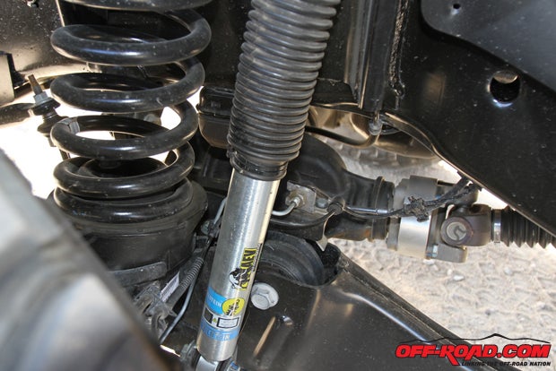 AEV retained the stock coil springs but moved the front axle two inches forward to center the large 40s in the carved-out wheel wells. Bilstein 5100 monotube shocks are fitted on each corner, and just behind it you can see the driveshaft extension for the axle relocation. 